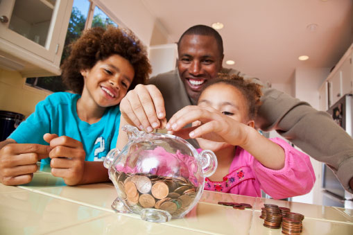 Father watching daughter put pennies into piggy bank